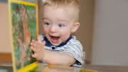 Baby mit Buch, lachen