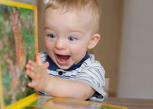 Baby mit Buch, lachen