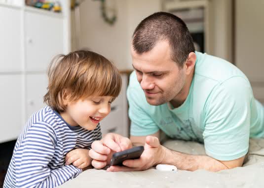 Medienerziehung bei Kindern. 3-6-9-12 Regel. Vater mit Sohn am Smartphone